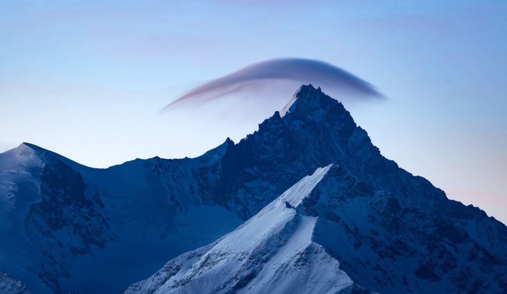 Snow-covered mountains under a lenticular cloud